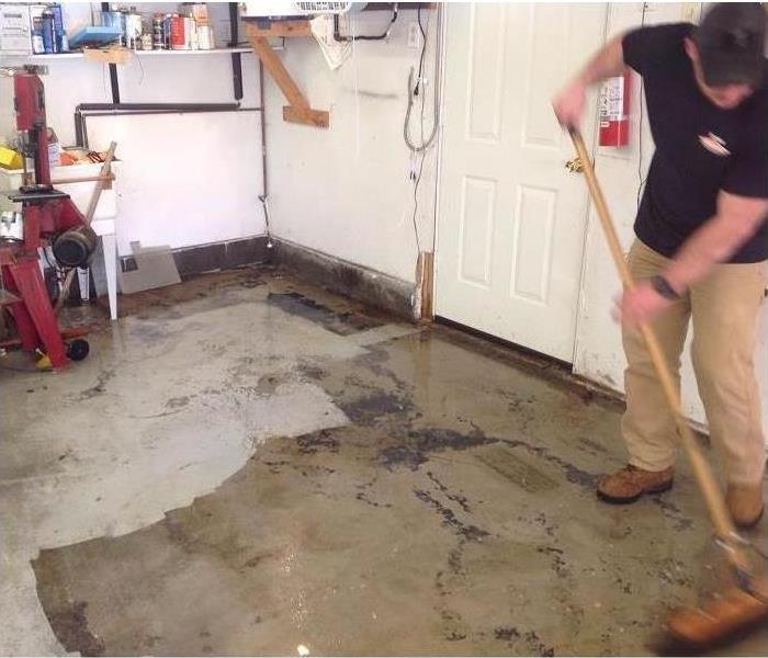 Technician cleaning with a broom sewage water